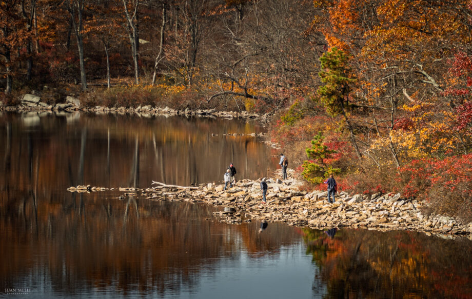 The rocky northern shoreline of Sunfish Pond, with fall color reflected in the clear mountain water.